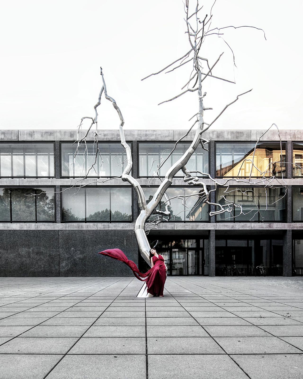 Frau in rotem Kleid vor Baum